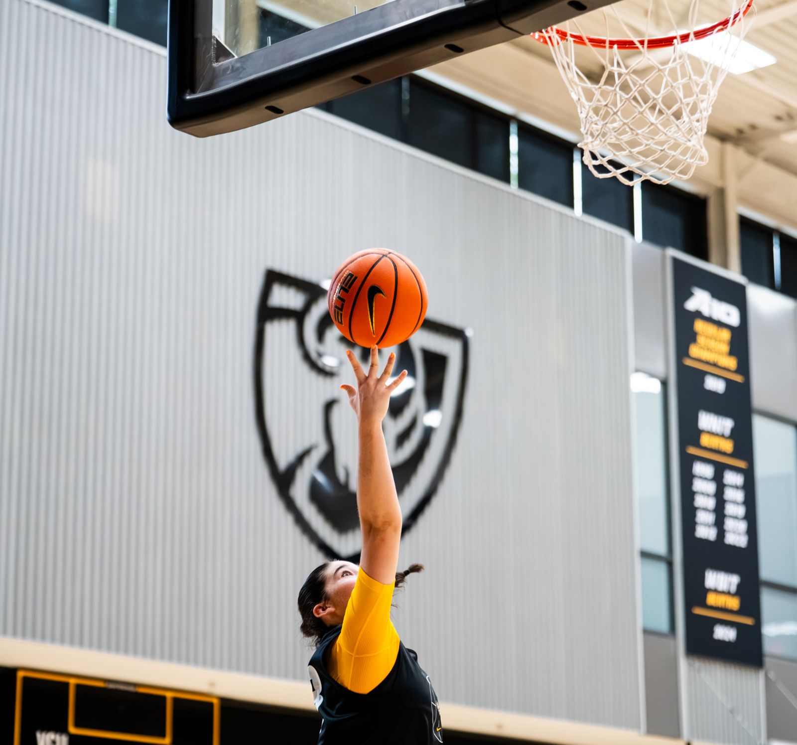 A VCU women’s basketball player finishes a layup under the Rams shield at practice