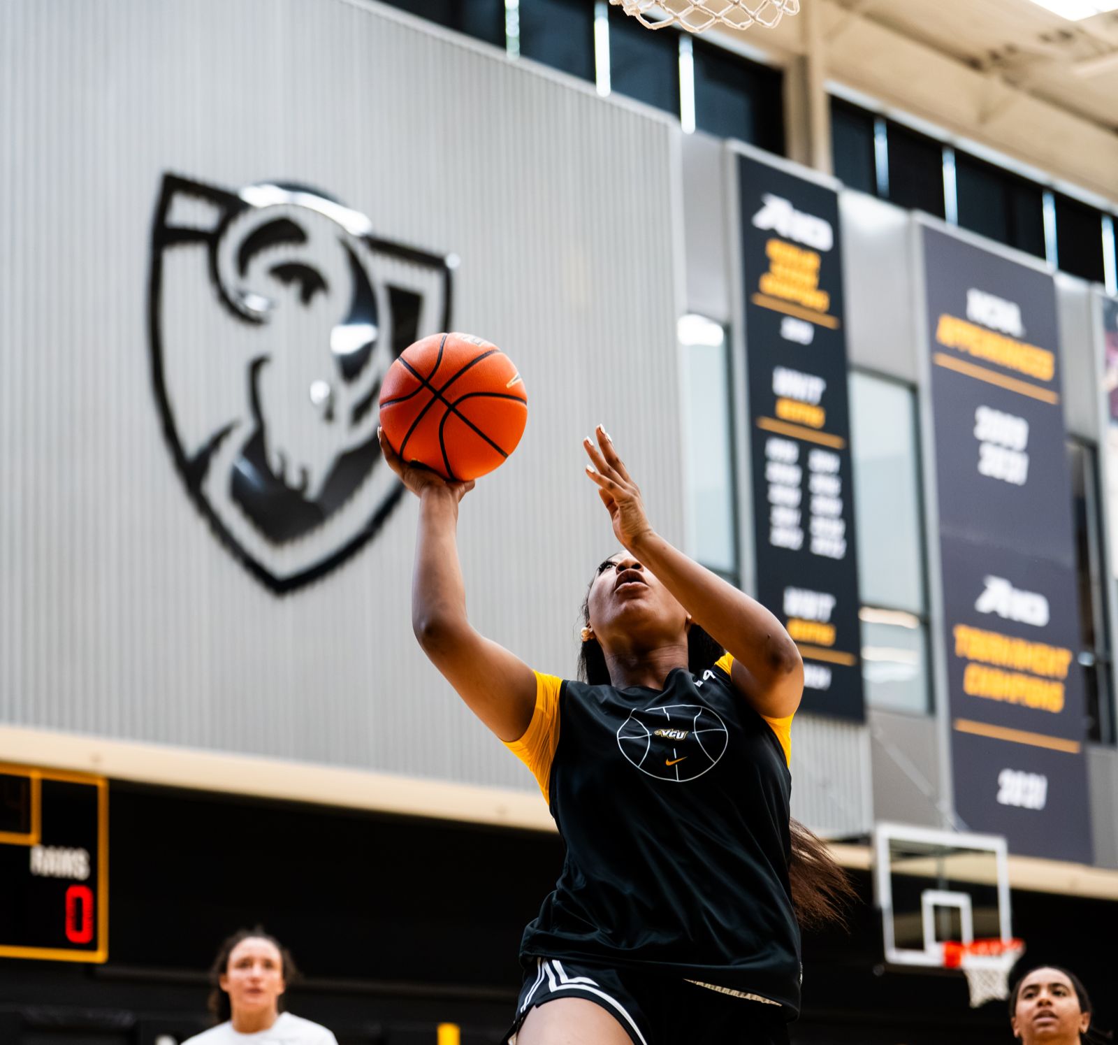 A VCU women’s basketball player goes up for a layup as teammates watch